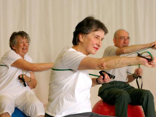 3 elderly people pushing arms forward while holding elastic straps